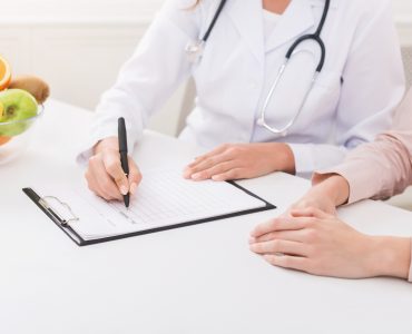 Nutritionist explaining personalized diet plan for patient during appointment in clinic, copy space